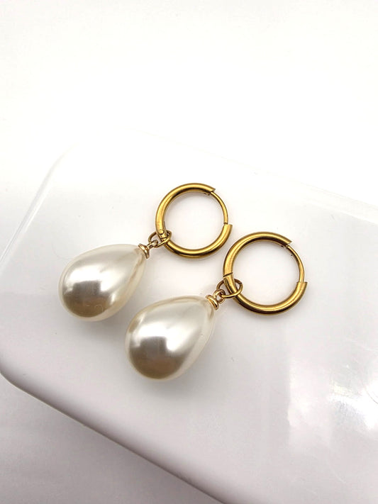 Pearl teardrop earrings with gold loops on a white background