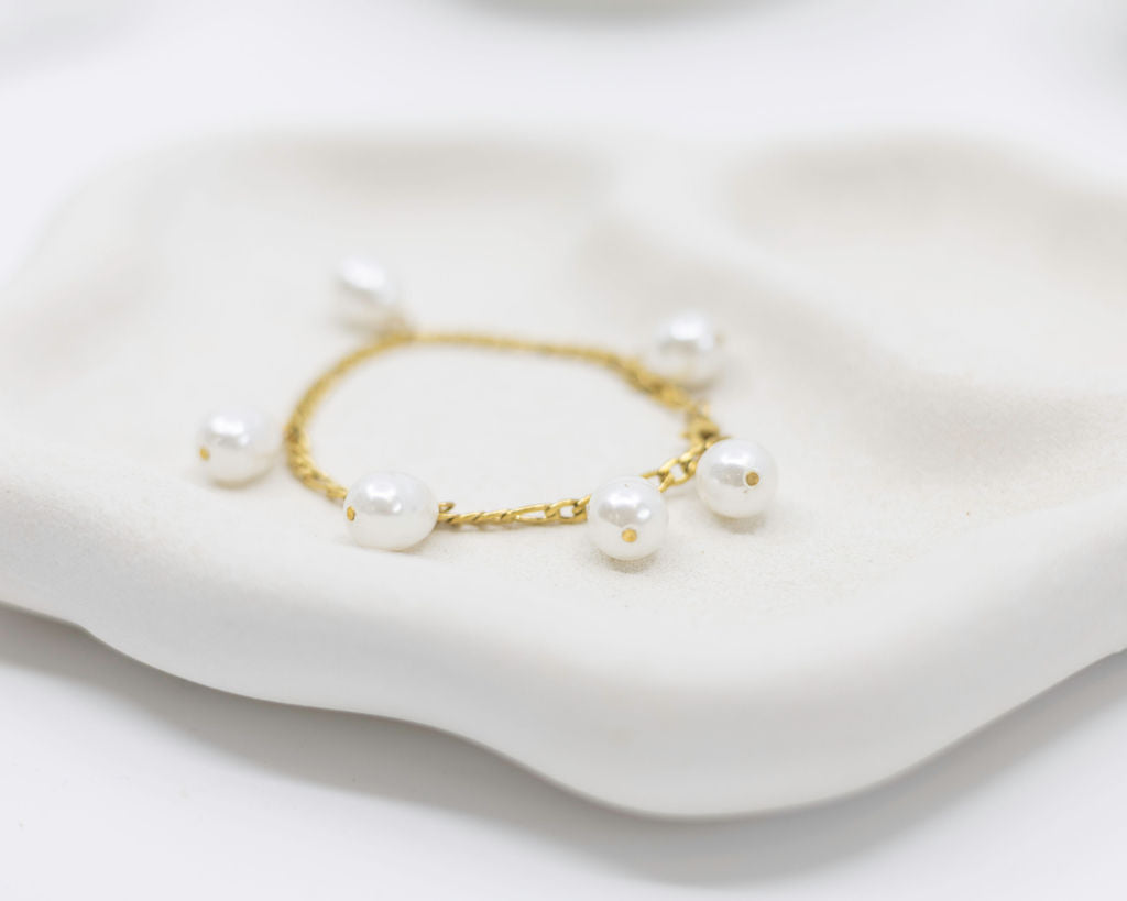 gold bracelet with pearl charms on white background