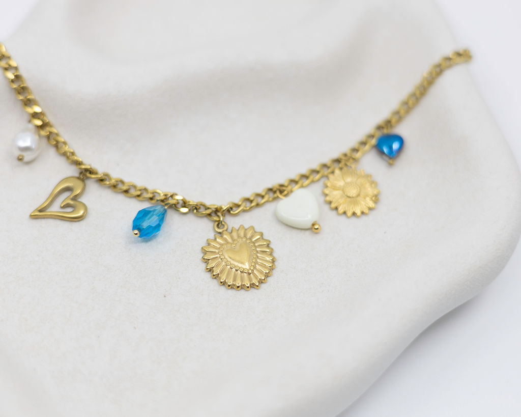 Gold necklace with various charms on a white surface