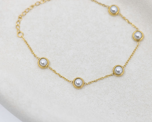 Gold bracelet with pearls on a light gray background