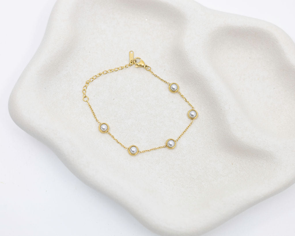 Gold bracelet with pearls on a white background