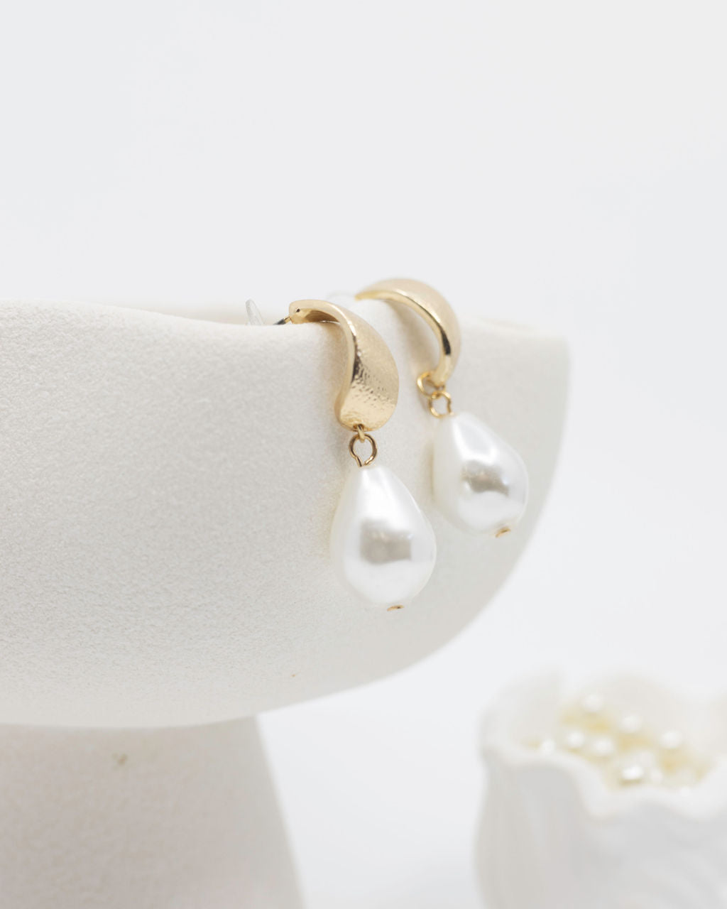 gold pearl earrings on white background
