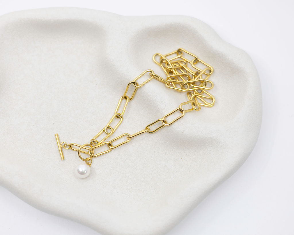 gold link chain and pearl necklace on white background