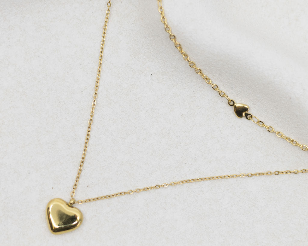 Gold heart-shaped pendant necklace on a white background