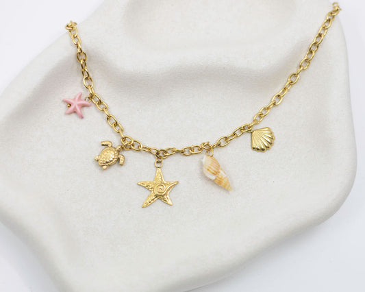 Gold chain bracelet with various charms on a white surface