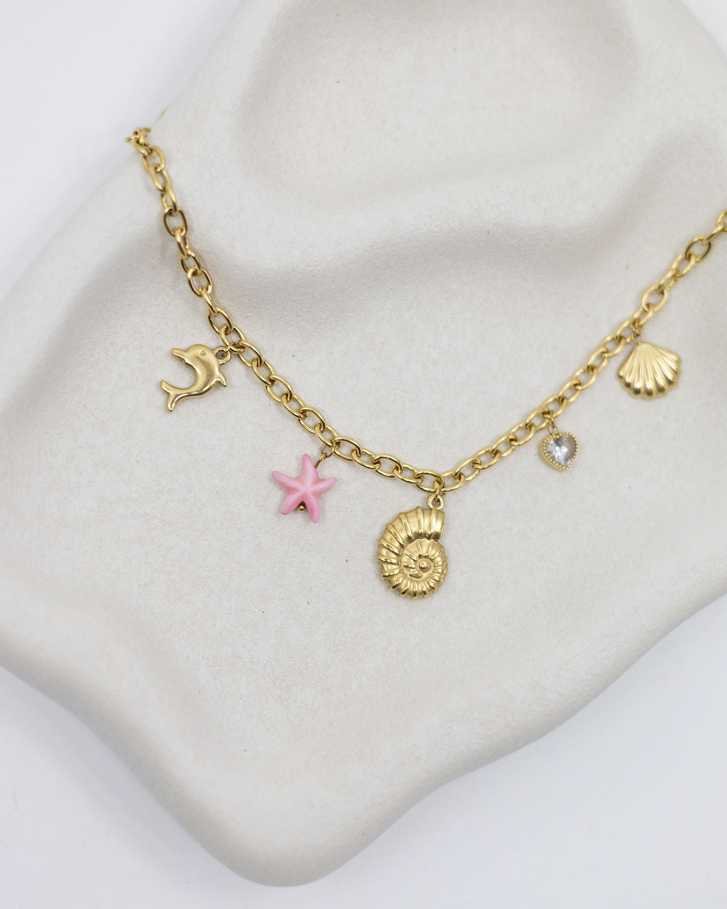 Gold bracelet with sea charms on a white surface