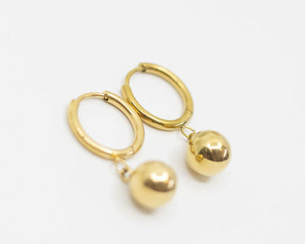 Gold earring with hoops and two gold ball drops on a white background