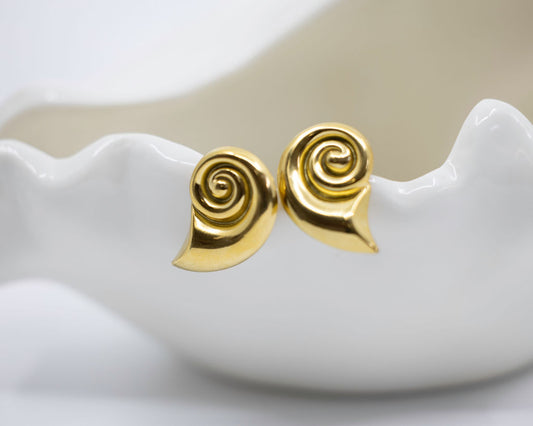 gold spiral shell earrings on white dish