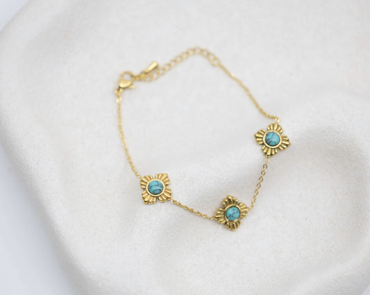 Gold bracelet with turquoise stones on a white background