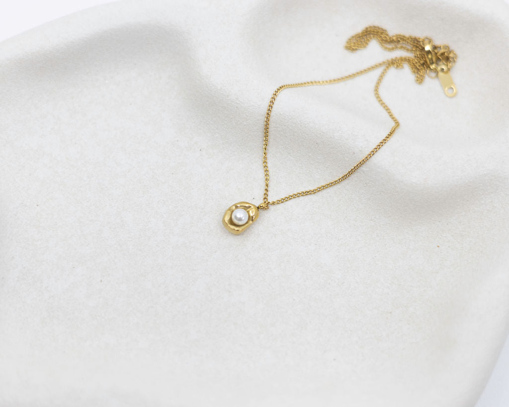 Gold necklace on a white fabric background