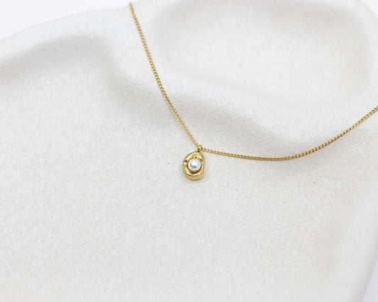 Gold necklace with a pearl pendant on a white background
