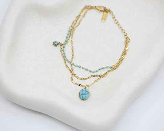 Gold necklace with turquoise stones on a white surface