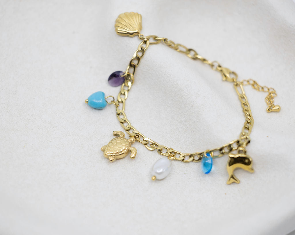 Gold bracelet with various charms on a white background