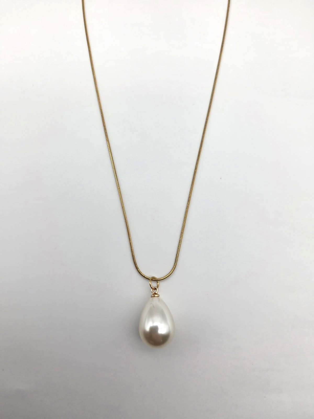 Pearl necklace on a thin chain against a light gray background