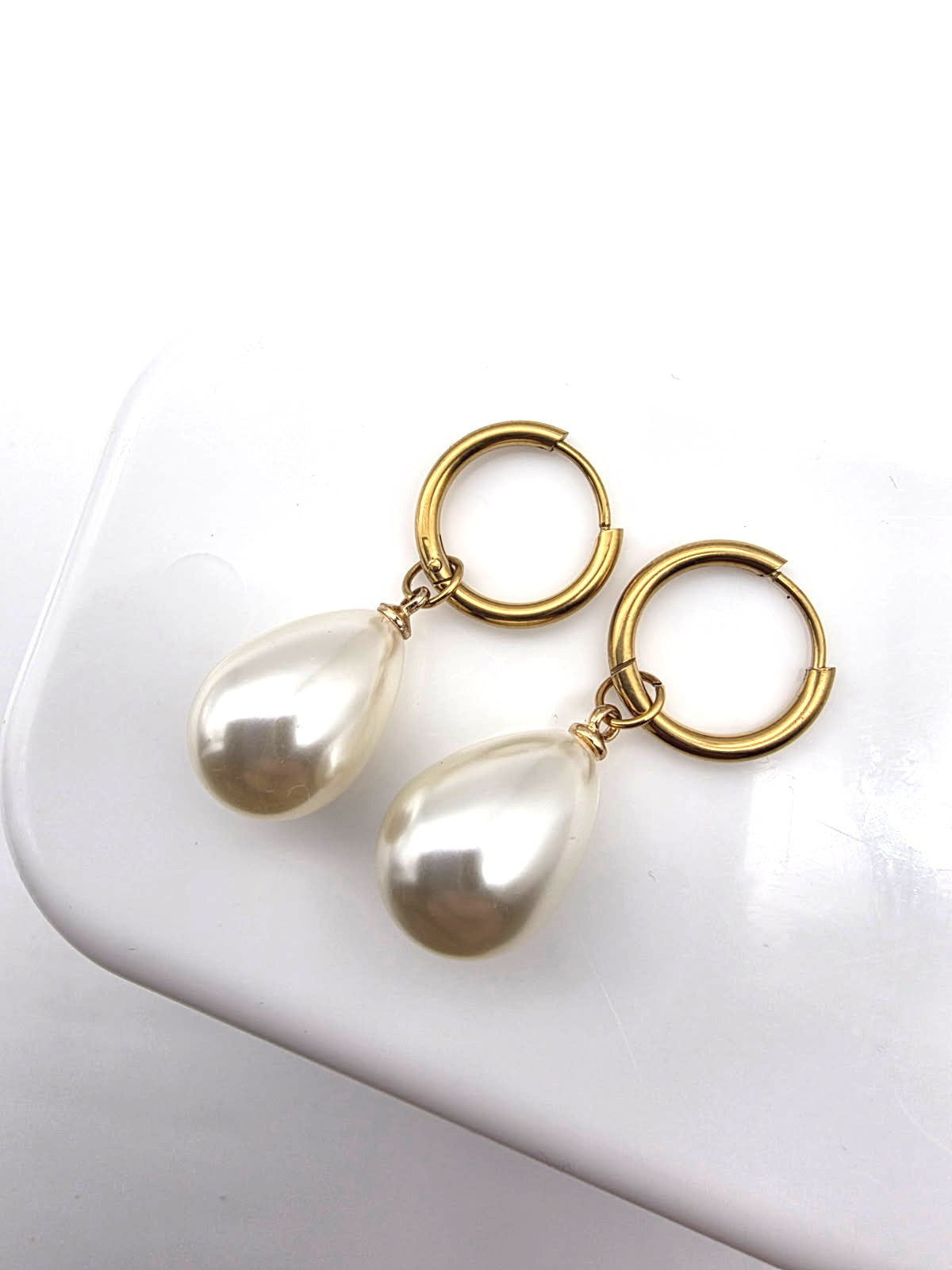 Pearl earrings with gold loops on a white surface