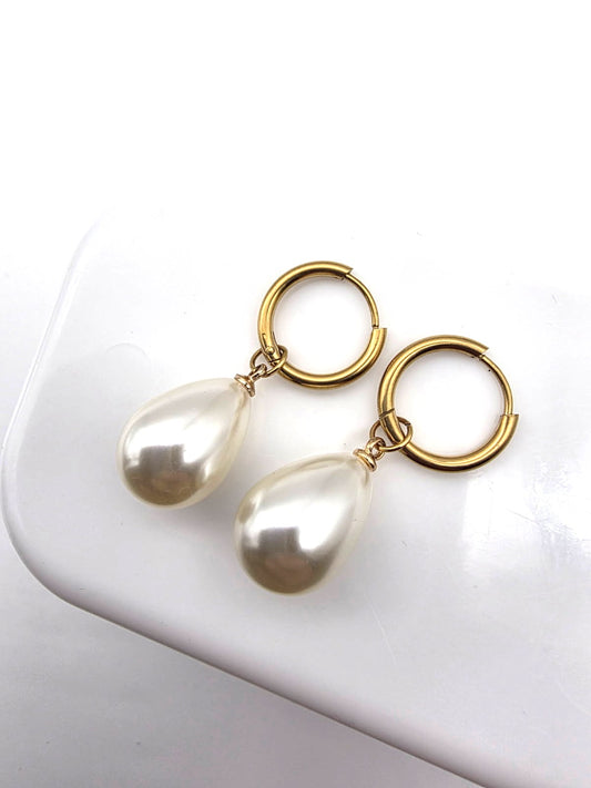 Pearl earrings with gold loops on a white surface