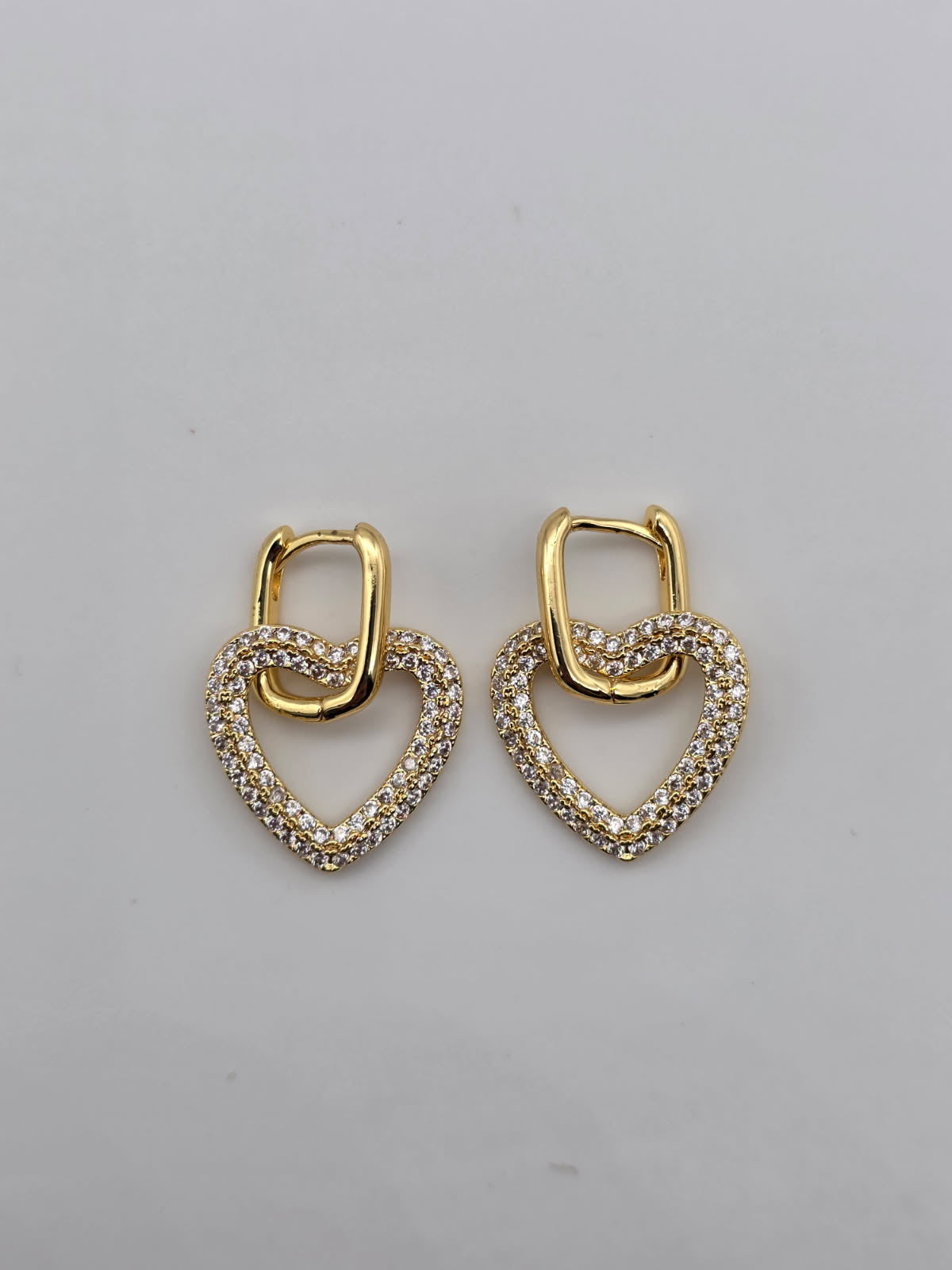 Pair of gold heart-shaped earrings on a gray background