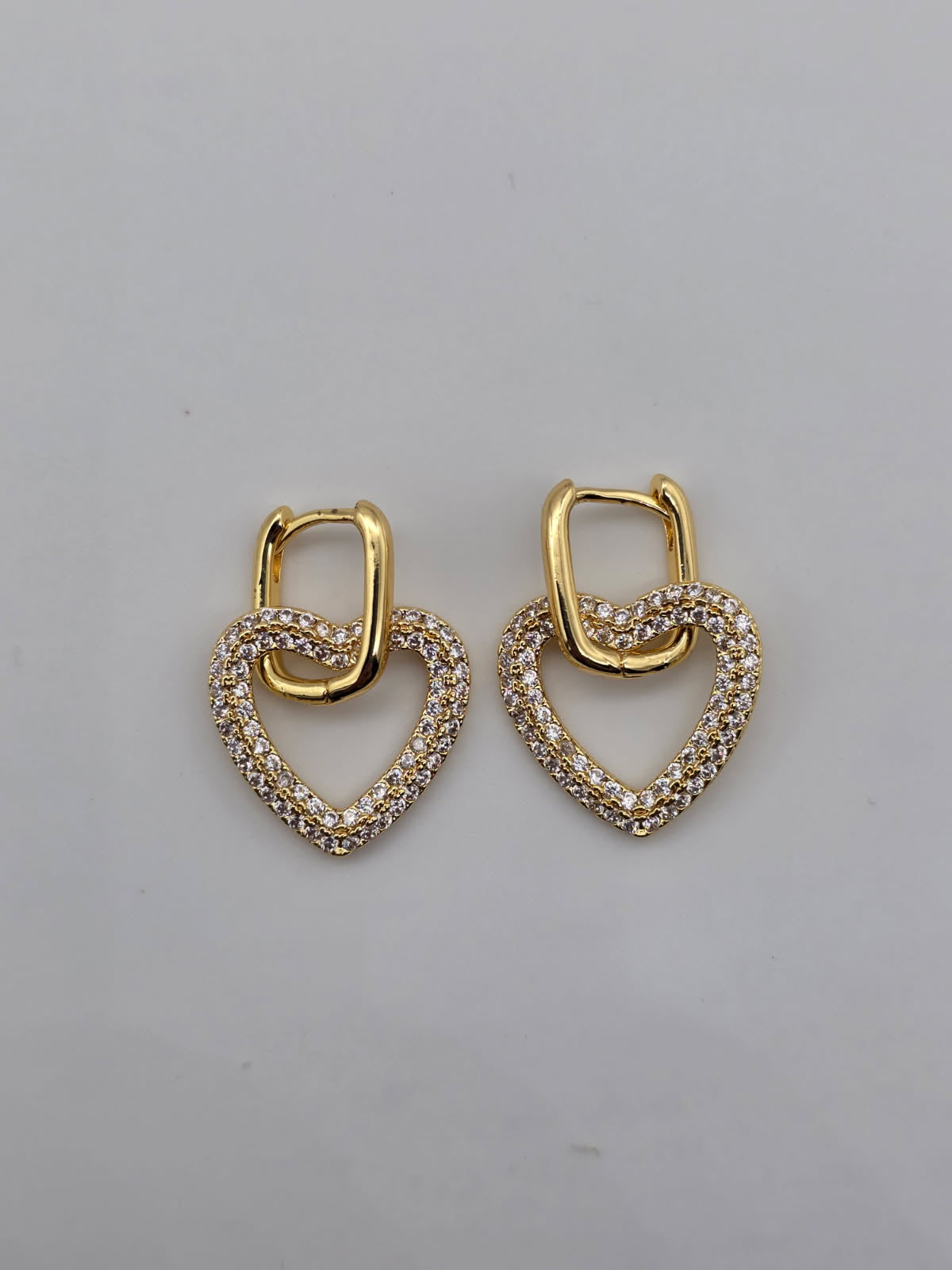 Pair of gold heart-shaped earrings on a gray background