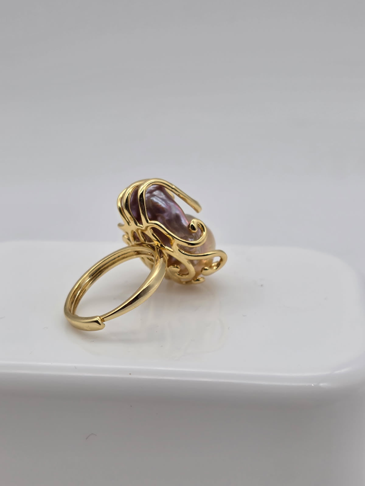 Gold ring with a freshwater baroque pearl on a white surface