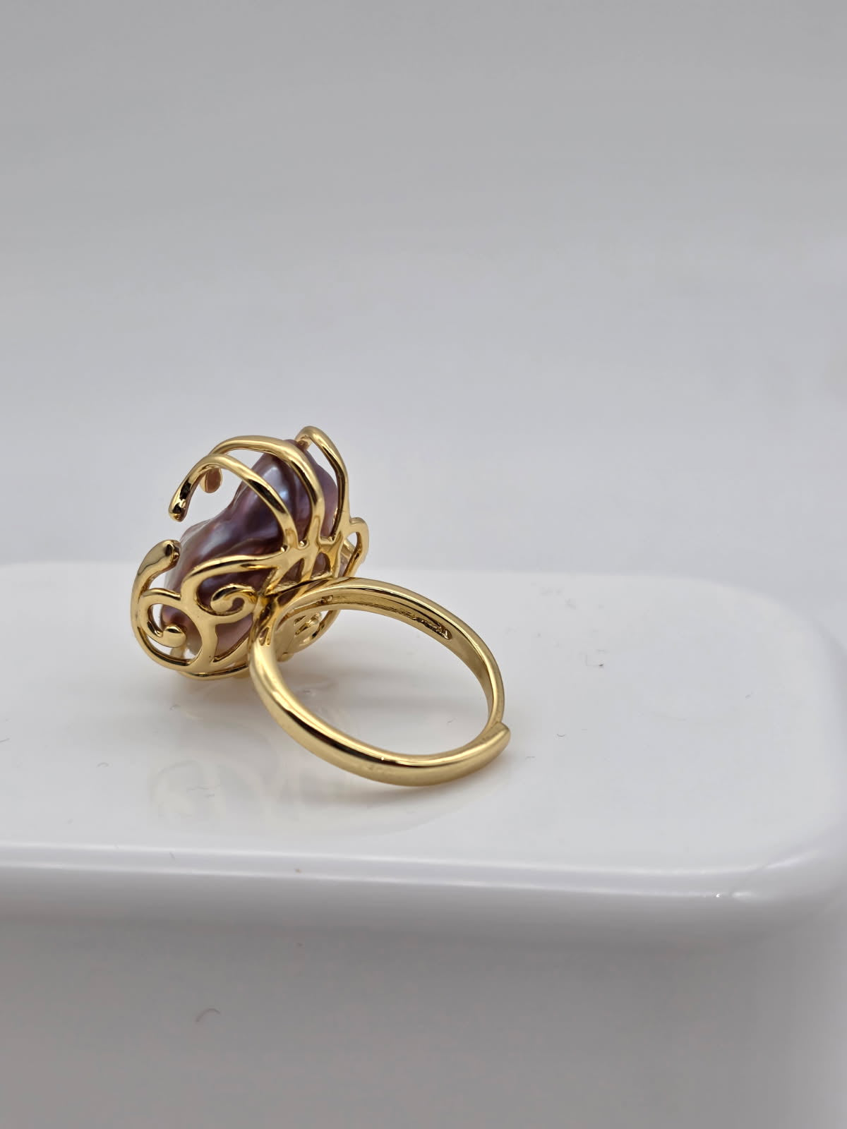 Gold ring with a freshwater baroque pearl on a white surface