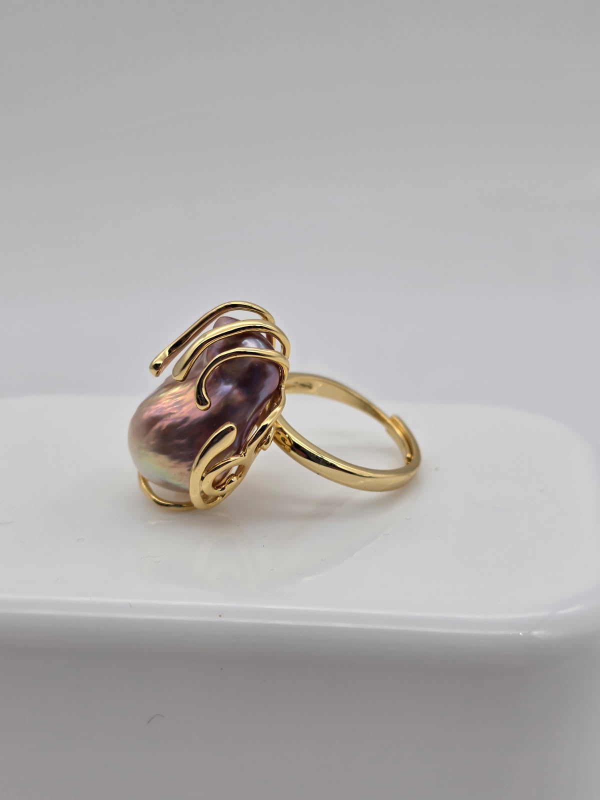 Gold ring with a freshwater baroque pearl on a white surface