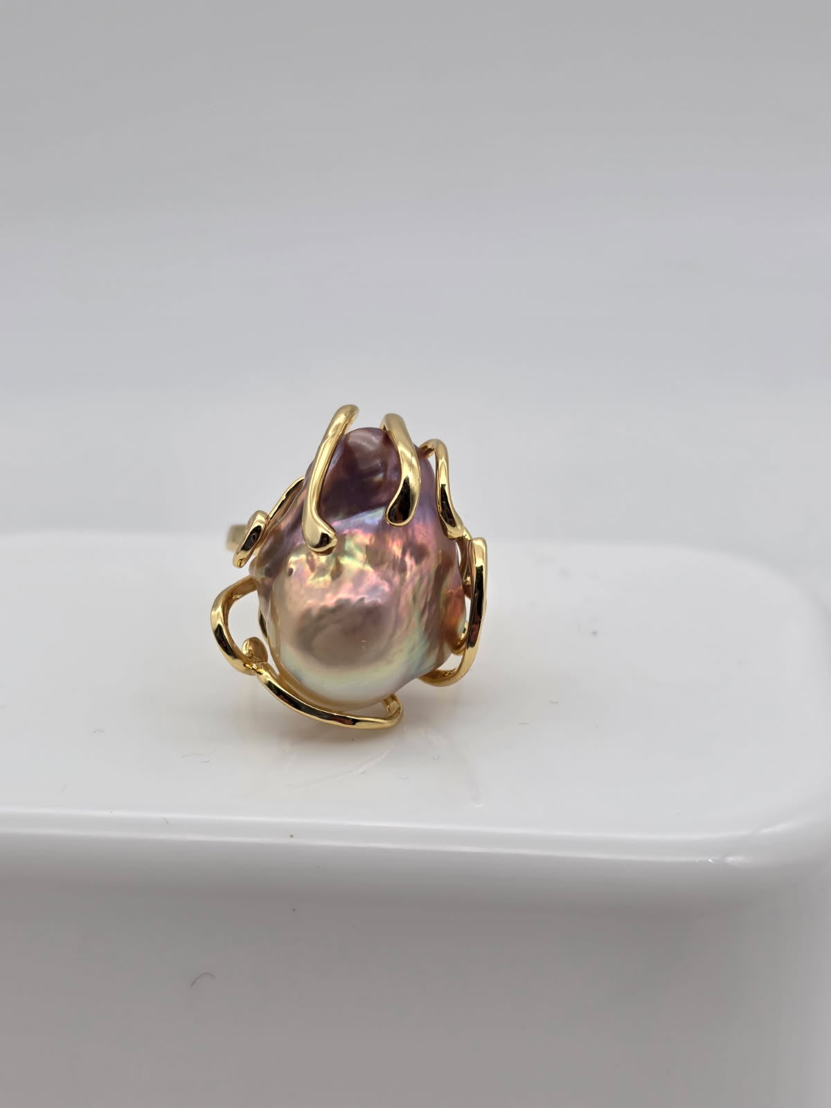 Gold ring with a freshwater baroque pearl on a white surface