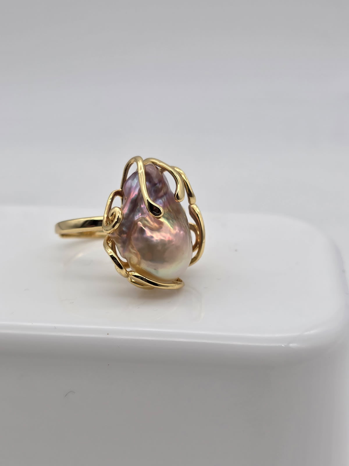 Gold ring with a freshwater baroque pearl on a white surface