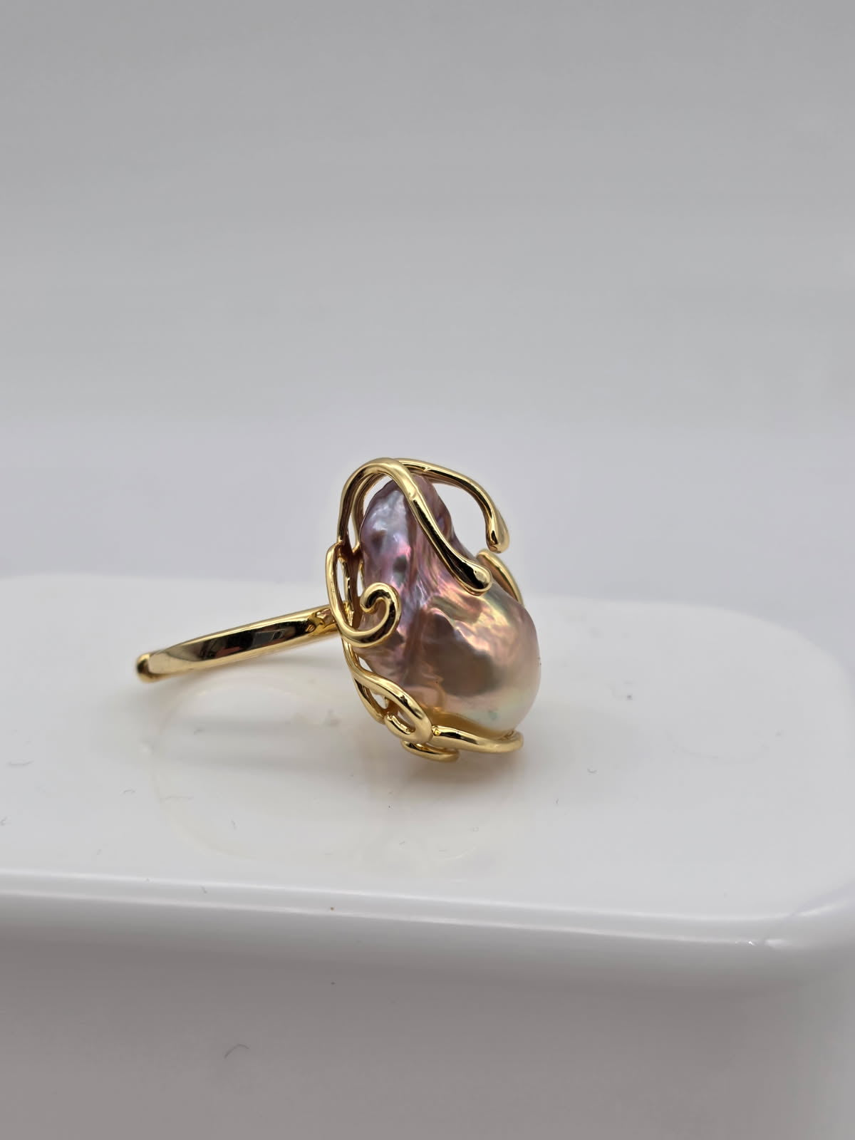 Gold ring with a freshwater baroque pearl on a white surface