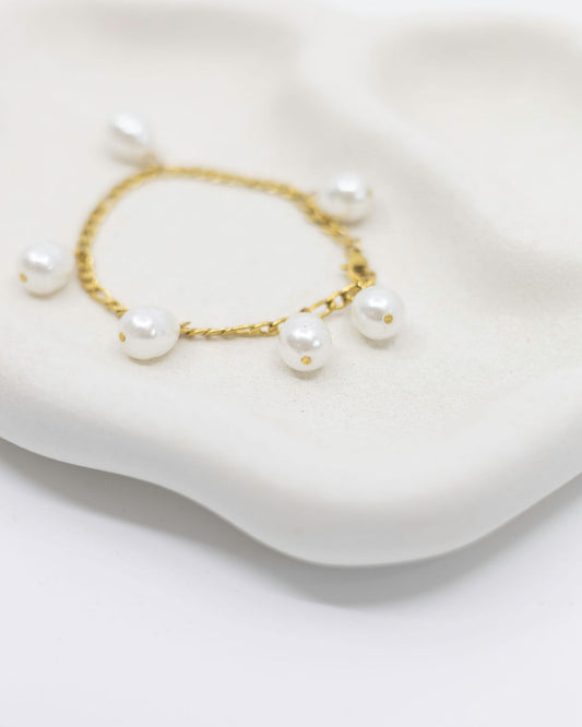 gold bracelet with pearl charms on white background