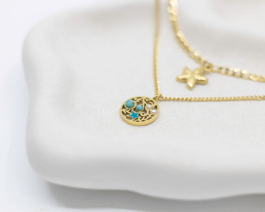 Gold necklaces with a turquoise pendant on a white dish
