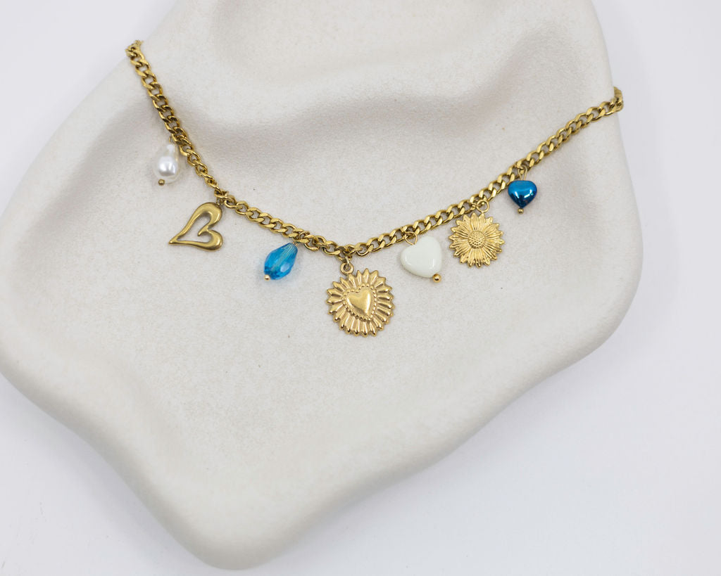Gold necklace with various charms against a white background