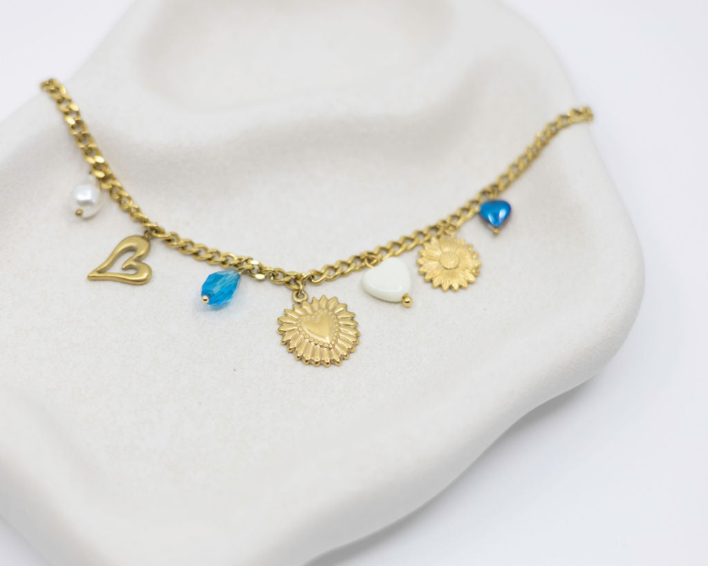 Gold necklace with various charms on a white stand