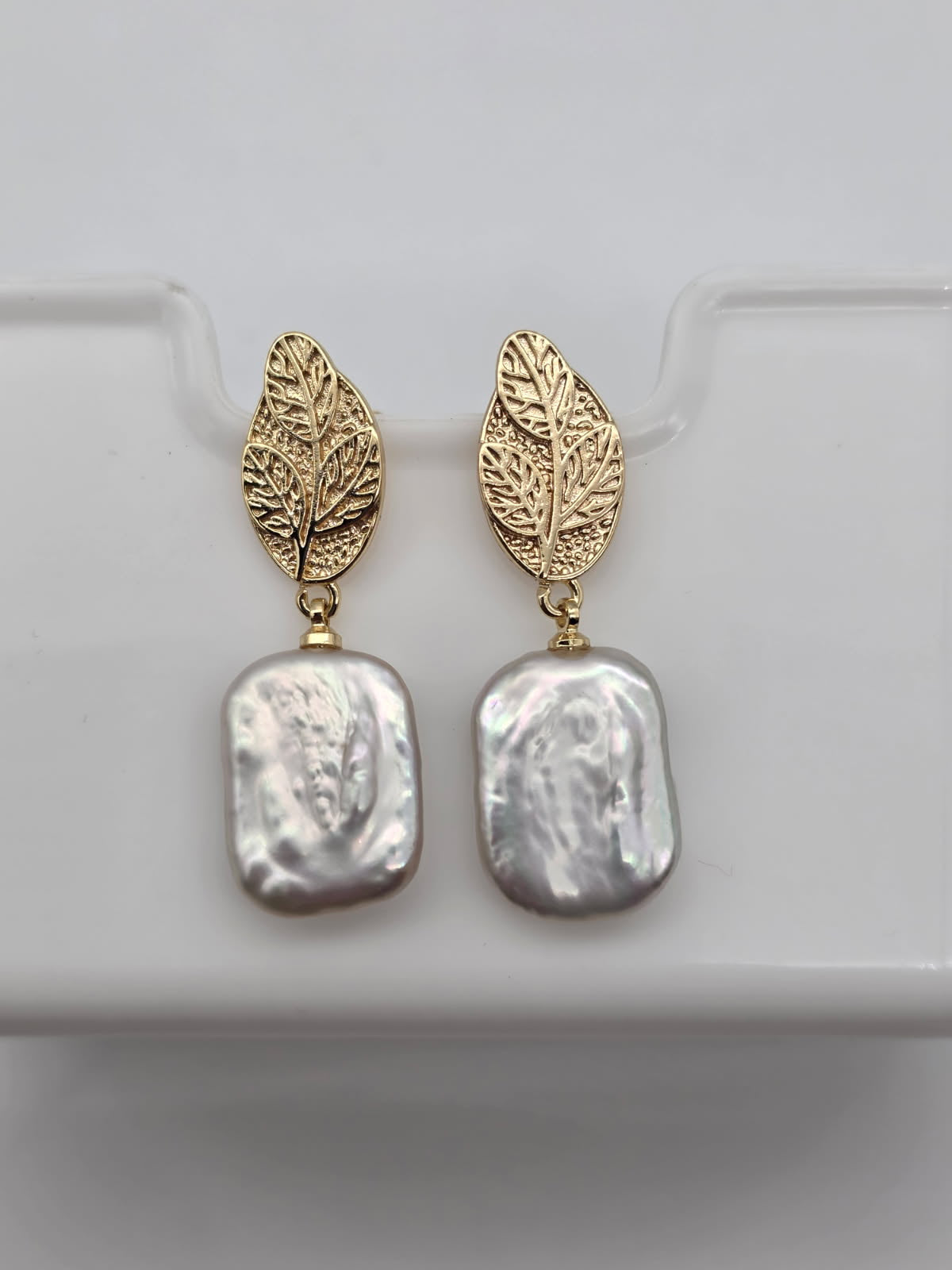 Gold leaf earrings with pearl  on a white background
