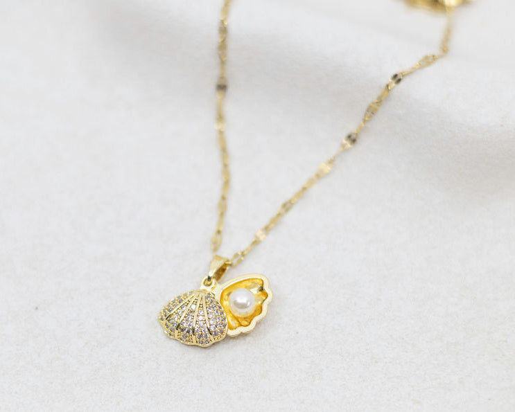 Gold necklace with a clam-shaped pendant on a white background