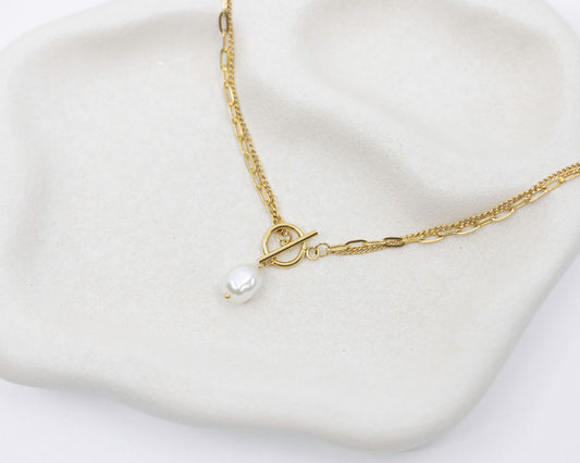 Gold necklace with a pearl pendant on a white background
