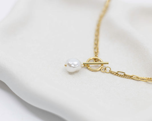 Gold necklace with a single pearl on a white background