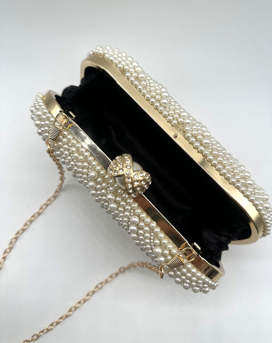 Pearl-embellished clutch bag with a chain strap on a white background