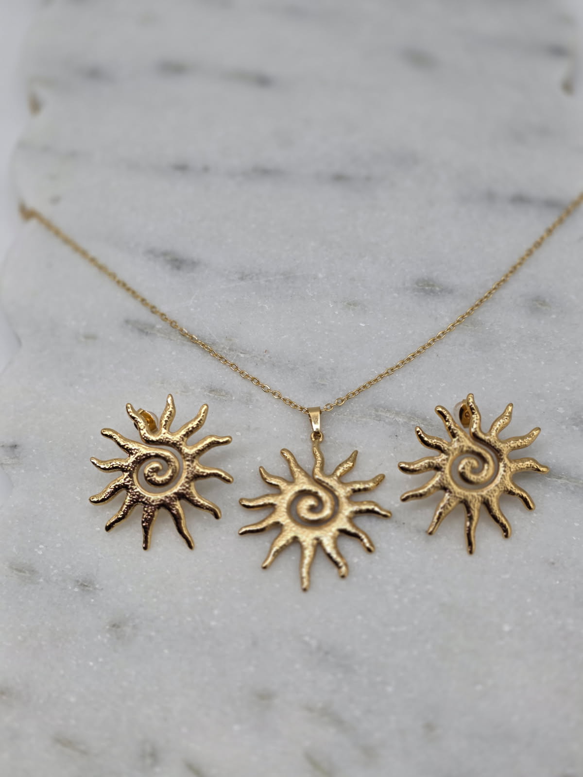 Gold sun-shaped necklace on a marble surface