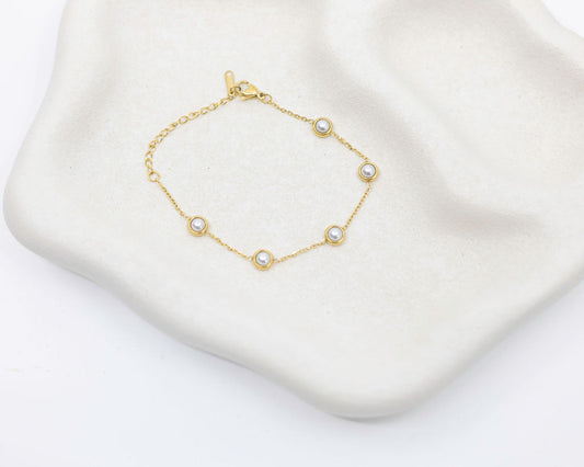Gold bracelet with pearls on a white surface
