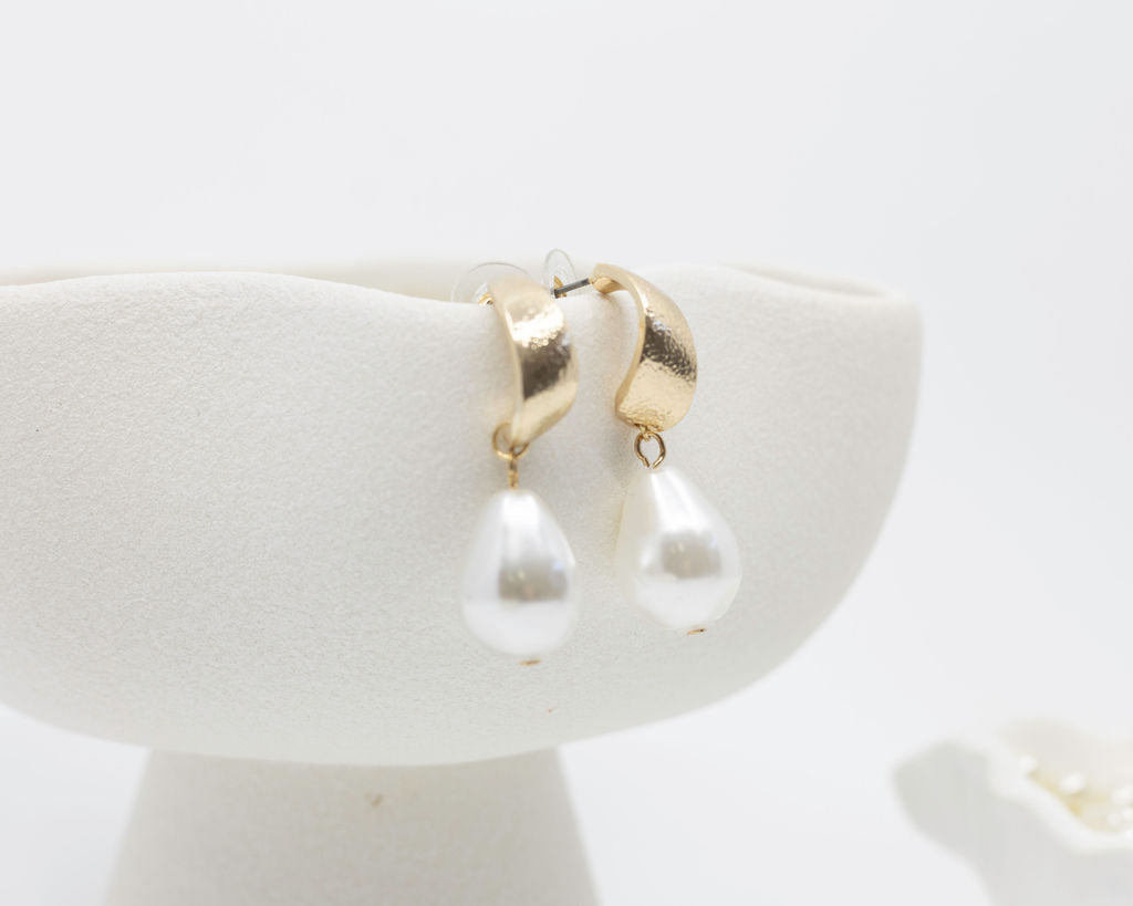 gold pearl earrings on white background