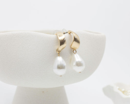 gold pearl earrings on white background