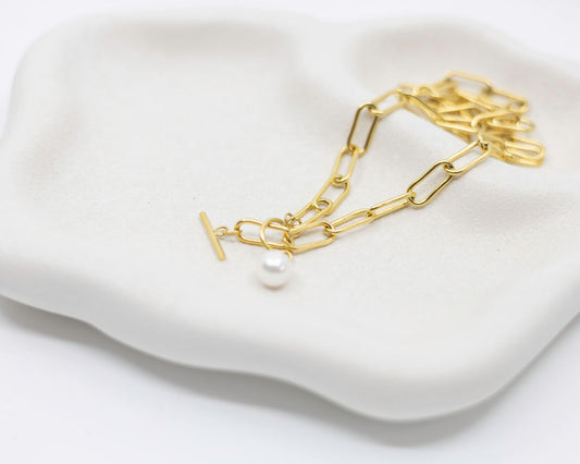 gold link chain and pearl necklace on white background