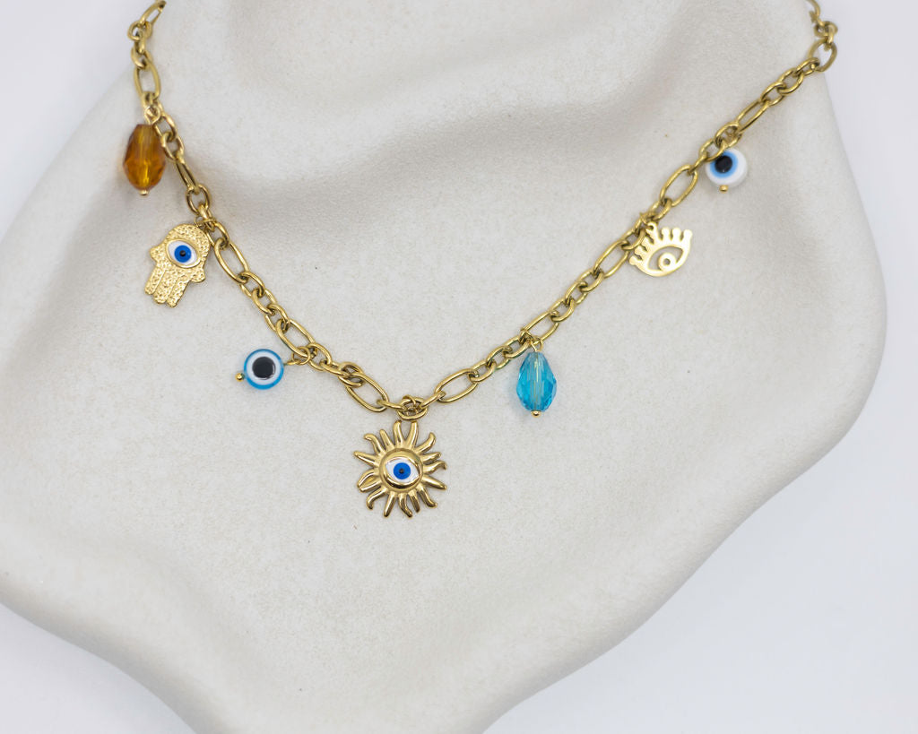 Gold chain necklace with various charms on a mannequin bust.