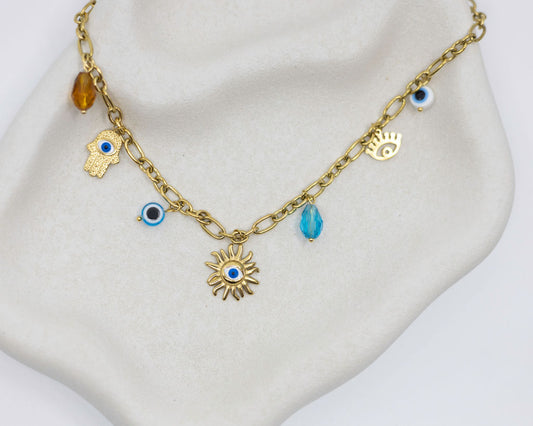 Gold chain necklace with various charms on a mannequin bust.