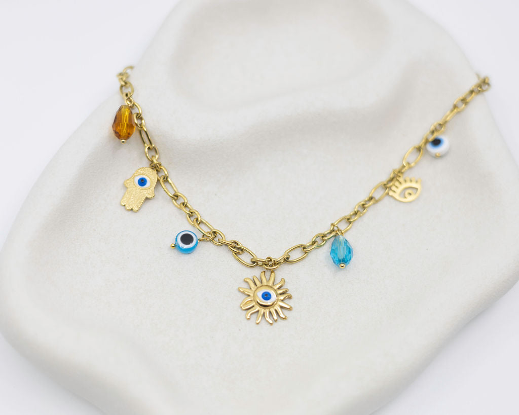 Gold bracelet with various charms on a white surface