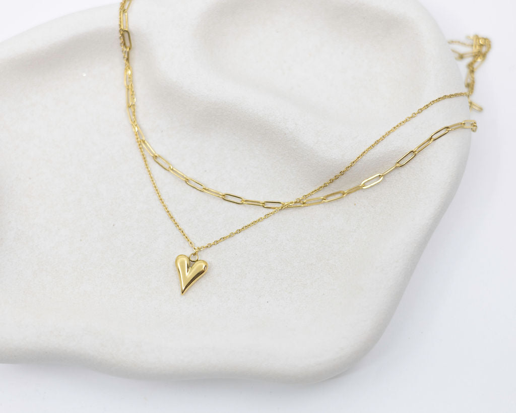 Gold heart-shaped necklace on a white surface