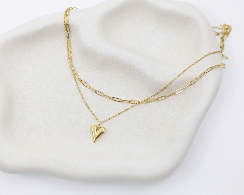 Gold heart-shaped necklace on a white stone surface