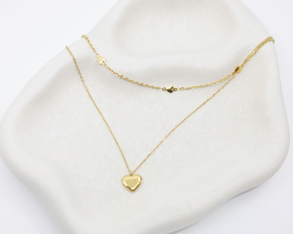 Gold heart-shaped necklace on a white stand