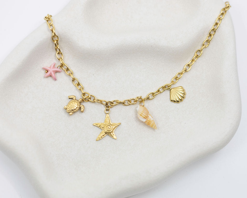Gold chain bracelet with various charms on a white surface