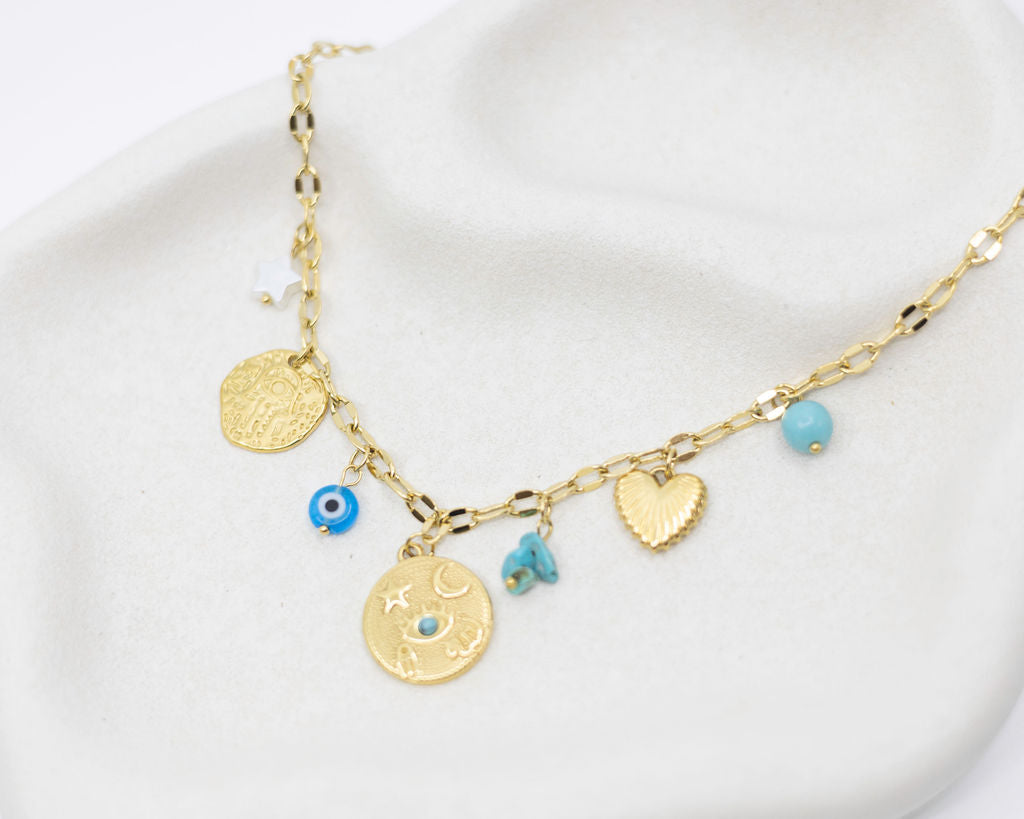 Gold necklace with various charms on a white background